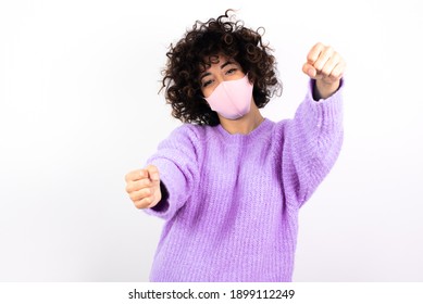 Young Beautiful Caucasian Woman Wearing Pink Medical Mask Standing Against White Wall,  Imagine Steering Wheel Helm Rudder Passing Driving Exam Good Mood Fast Speed