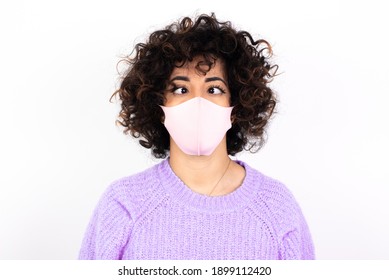 young beautiful caucasian woman wearing pink medical mask standing against white wall, making grimace and crazy face, screaming out of control, funny lunatic expressing freedom and wild.