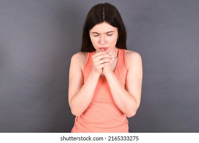 young beautiful Caucasian woman wearing orange T-shirt over studio grey wall holding oneself, feels very cold outside, hopes that will not get cold - Powered by Shutterstock