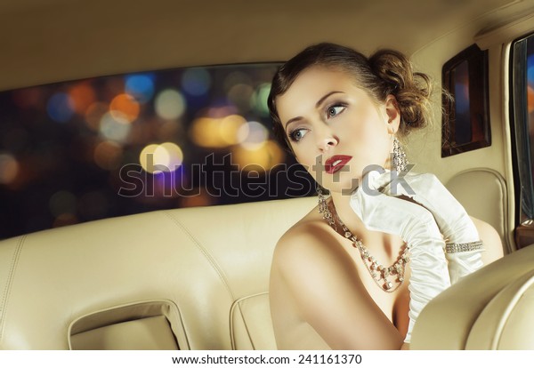 Young and beautiful celebrity woman sitting in a\
luxury car