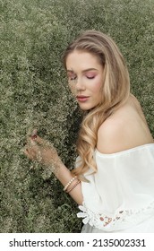 Young Beautiful Charming Blonde Woman Surrounded By White Gypsophila Flowers Bush In Garden, Sleeping Beauty Fairy Tale Cosplay