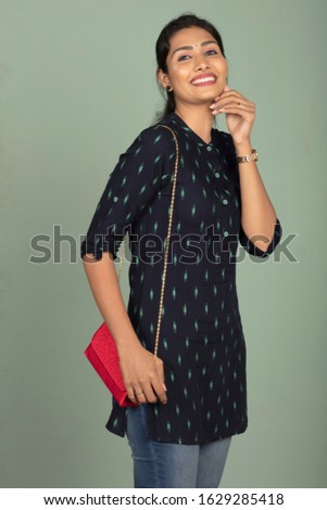 young beautiful charming indian woman posing casually with handbag, indoor shot