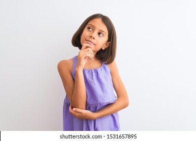 Young Beautiful Child Girl Wearing Purple Casual Dress Standing Over Isolated White Background With Hand On Chin Thinking About Question, Pensive Expression. Smiling With Thoughtful Face. Doubt