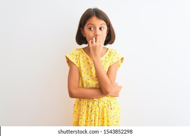 Young Beautiful Child Girl Wearing Yellow Floral Dress Standing Over Isolated White Background Looking Stressed And Nervous With Hands On Mouth Biting Nails. Anxiety Problem.