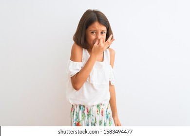 Young Beautiful Child Girl Wearing Casual Dress Standing Over Isolated White Background Smelling Something Stinky And Disgusting, Intolerable Smell, Holding Breath With Fingers On Nose. Bad Smells.