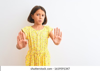 Young Beautiful Child Girl Wearing Yellow Floral Dress Standing Over Isolated White Background Moving Away Hands Palms Showing Refusal And Denial With Afraid And Disgusting Expression. Stop