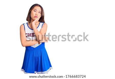 Young beautiful chinese girl wearing cheerleader uniform thinking looking tired and bored with depression problems with crossed arms. 