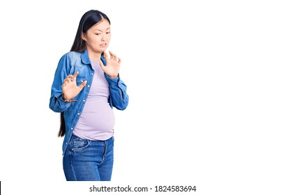 Young Beautiful Chinese Woman Pregnant Expecting Baby Disgusted Expression, Displeased And Fearful Doing Disgust Face Because Aversion Reaction. 