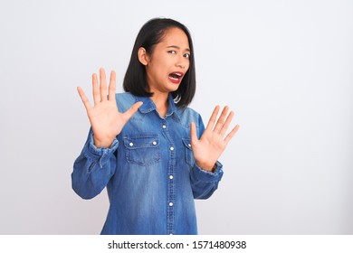 Young Beautiful Chinese Woman Wearing Denim Shirt Standing Over Isolated White Background Afraid And Terrified With Fear Expression Stop Gesture With Hands, Shouting In Shock. Panic Concept.