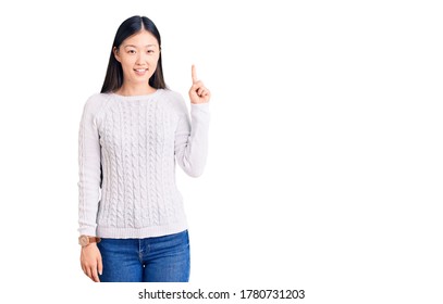 Young beautiful chinese woman wearing casual sweater showing and pointing up with finger number one while smiling confident and happy.  - Shutterstock ID 1780731203