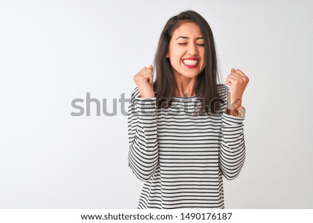 Young beautiful chinese woman wearing striped t-shirt standing over isolated white background excited for success with arms raised and eyes closed celebrating victory smiling. Winner concept.