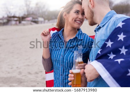 Young beautiful couple with american flag having fun on beach. Teenagers with american flag having fun.