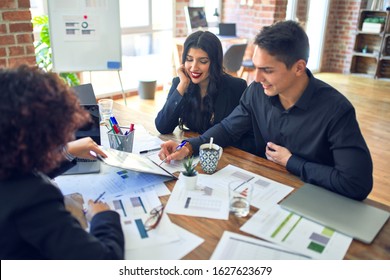 Young Beautiful Couple Applying For Mortgage. Sitting Smiling Happy Meeting With Real State Agent Signing Mortgage Loan At Bank