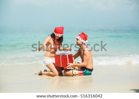 young beautiful couple celebrates Christmas and New Year on the beach and the sea, give gifts, Christmas tree, flashlights, the beach and the holiday spirit, 2017
