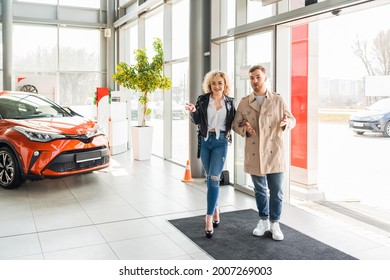 Young Beautiful Couple Enters To Car Dealership