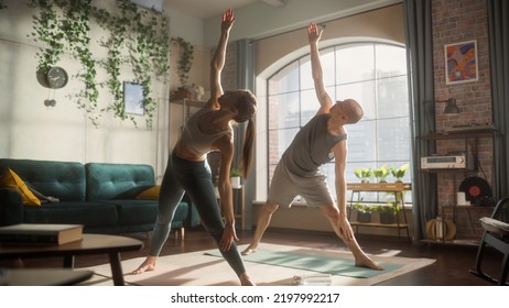 Young Beautiful Couple Exercising Together, Stretching And Practising Yoga In The Morning In Bright Sunny Loft Apartment. Healthy Lifestyle, Fitness, Wellbeing, Mindfulness And Bodycare Concept.