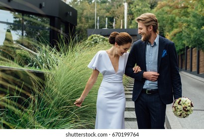 young and beautiful couple of just married in beautiful suits with bouquet walk about nice green territory