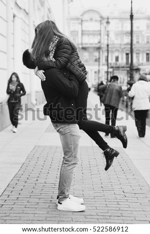 Young beautiful couple in love kissing and hugging at city street on autumn, fall, or spring day. Full length outdoors portrait. Lifestyle.