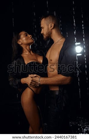 Young beautiful couple making love in the shower in monochrome. passionate kiss underwater. dark room