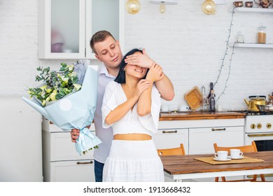 Young beautiful couple a man gives a woman flowers for a holiday at home