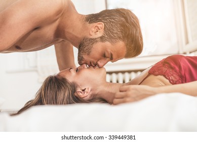 Young beautiful couple on a bed - Two lovers in the sleeping room, kissing on the bed 