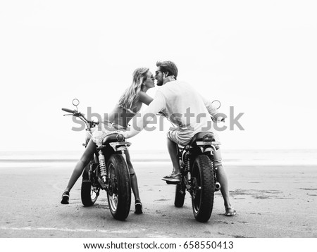 Young beautiful couple on motorcycles kissing on the beach, outdoor portrait, bearded guy, blonde girl, travel together, ocean, sea