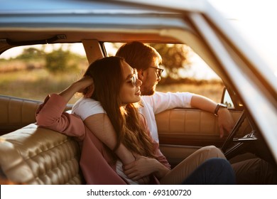Young beautiful couple relaxing together while sitting inside a retro car
