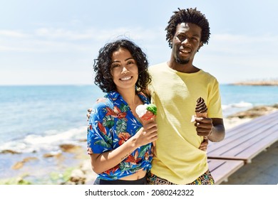 Young beautiful couple smiling happy eating ice cream at the beach.