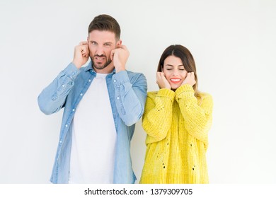 Young Beautiful Couple Togheter Over Isolated Background Covering Ears With Fingers With Annoyed Expression For The Noise Of Loud Music. Deaf Concept.