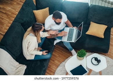 Young Beautiful Couple Using A Laptop While Relaxing At Home On The Couch Together Shot From Above