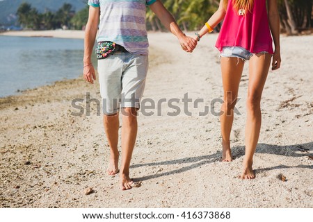 young beautiful couple walking on tropical beach in thailand, holding hands, hipster outfit, casual style, honey moon, vacation, summertime, sunny, legs close-up, details, bare foot