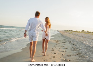 Young beautiful couple walks along the seashore at sunset. Honeymoon. Romantic trip. - Powered by Shutterstock