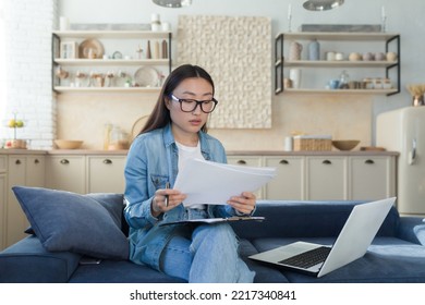 Young Beautiful Creative Woman Asian Writer, Journalist. He Sits At Home On The Sofa With A Laptop And Writes A Book, An Essay, A Script, An Article. Holds Paper And Pen.