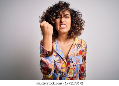 Young Beautiful Curly Arab Woman Wearing Floral Colorful Shirt Standing Over White Background Angry And Mad Raising Fist Frustrated And Furious While Shouting With Anger. Rage And Aggressive Concept.