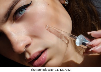 Young Beautiful Curly Woman Uses Serum For Face. The Concept Of Facial Skin Care.