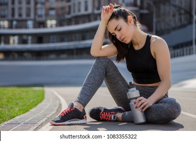 A Young Beautiful Dark-haired Athletic Girl Is Hanging Out In Sports, Warming Up And Performing Sports Exercises For Her Health And A Strong Healthy Body On A Treadmill On The City Street Cycle Track