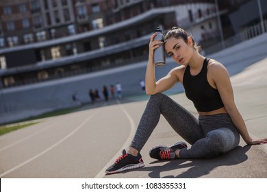 A Young Beautiful Dark-haired Athletic Girl Is Hanging Out In Sports, Warming Up And Performing Sports Exercises For Her Health And A Strong Healthy Body On A Treadmill On The City Street Cycle Track