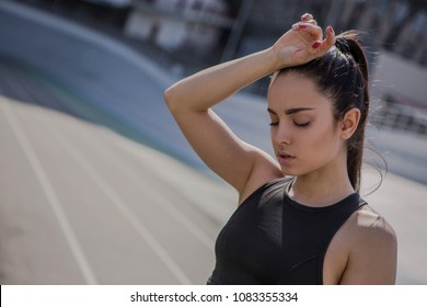 A Young Beautiful Dark-haired Athletic Girl Is Hanging Out In Sports, Warming Up And Performing Sports Exercises For Her Health And A Strong Healthy Body On A Treadmill On The City Street Cycle Track