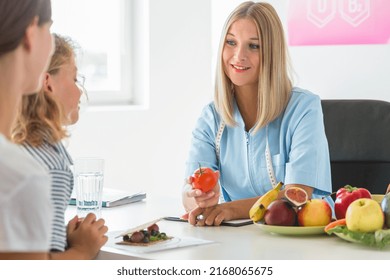 Young Beautiful Dietitian Is Standing In The Office Holding An Apple