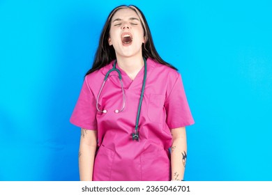 young beautiful doctor woman standing over blue background angry and mad screaming frustrated and furious, shouting with anger. Rage and aggressive concept. - Shutterstock ID 2365046701