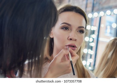 Young beautiful european woman is preparing for the occassion at a beauty salon. She is getting professional make up service by makeup artist.