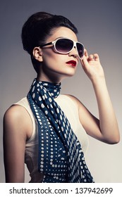 Young Beautiful Fashion Model With A Spotted Blue Scarf Posing On Gray Background