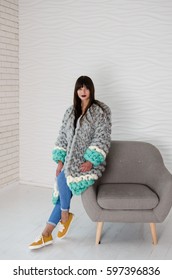 Young Beautiful Fashionable Woman Standing Near Chair In Merino Wool Jacket