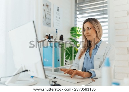 Young beautiful female doctor working on laptop in doctor's office. Physician doing paperwork and administration.