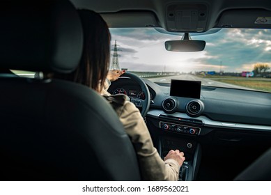 Young beautiful female driving an automobile on a highway .