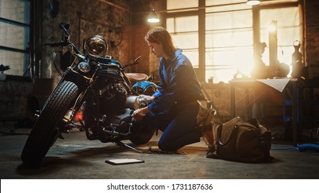 Young Beautiful Female Mechanic is Working on a Custom Bobber Motorcycle. Talented Girl Wearing a Blue Jumpsuit. She Uses a Ratchet Spanner to Tighten Nut Bolts. Creative Authentic Workshop Garage. - Powered by Shutterstock