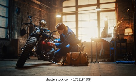 Young Beautiful Female Mechanic is Working on a Custom Bobber Motorcycle. Talented Girl Wearing a Blue Jumpsuit. She Uses a Ratchet Spanner to Tighten Nut Bolts. Creative Authentic Workshop Garage. - Powered by Shutterstock