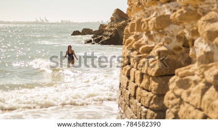 A young beautiful female model enjoying a photo session in Cadiz. A swimsuit brunette model near a castle in ruins in Cadiz. Beautiful latin girl in swimsuit
