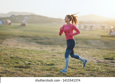 Young Beautiful Female Runner Jogging At Sunset In Mountains.