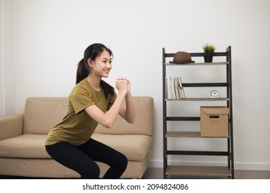 Young Beautiful Fitness Asian Woman Doing Squat Sit Up Exercise Workout At Home. Attractive Female Warming Up Body Training Wearing Sportswear. Side View Sporty Girl Stretching Warm Up Cardio Body.